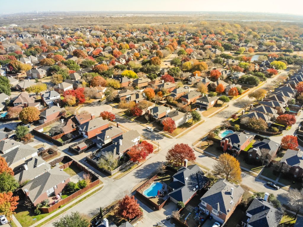 Aerial view lakeside subdivision with large house and colorful autumn leaves near Dallas