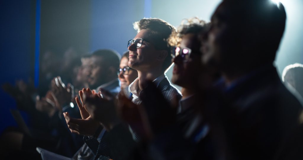 Young Man Sitting in a Crowded Audience